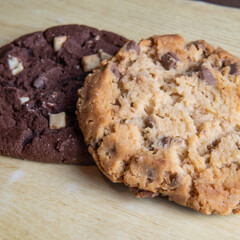 cookie with pieces of black and white chocolate on a wooden table.
