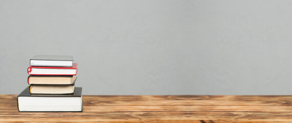 A stack of books on a wooden table.