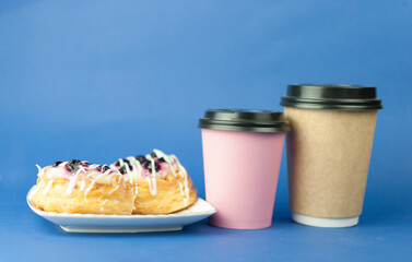 disposable paper coffee cup of hot coffee and sweet pastries on blue background. Coffee time, breakfast
