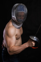 Matured man with naked muscular torso in fencing helmet and epee