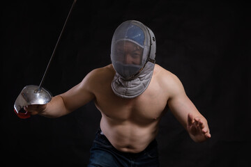 Matured man with naked muscular torso in fencing helmet and epee
