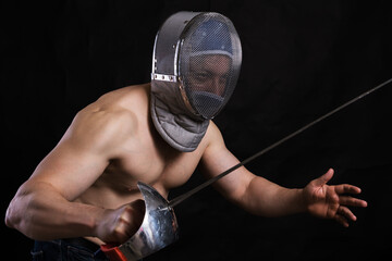Matured man with naked muscular torso in fencing helmet and epee