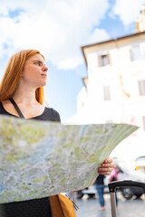 serious girl is searching accomodation using a paper map of the city