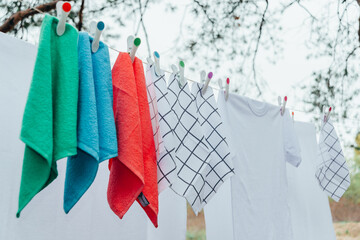 Washed colorful clothes on clothesline with plastic pins. Selective focus.