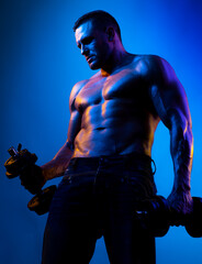 Fototapeta na wymiar Muscular bodybuilder guy doing exercises with dumbbells isolated on blue neon. Naked athlete with strong body. Shirtless hunk with perfect abs.