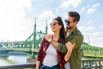 Fototapeta premium A couple enjoying a sunny day in front of the liberty bridge in Budapest
