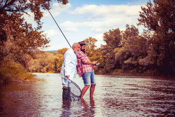 Two men fishing on river. Mature man with adult son. Fishing on the lake. If wishes were fishes. Fisherman with rod and fish. Senior friends fishing by the lake. Friends men with rod and net.