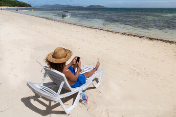 Male with curly hair, wearing blue swimsuits, checking his smartphone