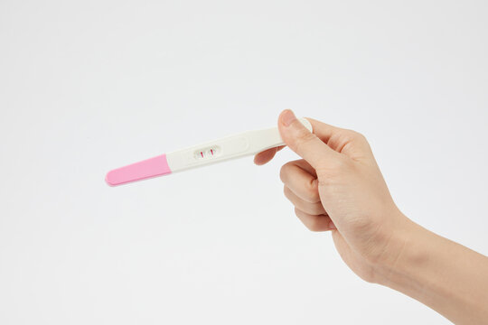 Closeup Of A Person Holding A Positive Pregnancy Test On A White Background