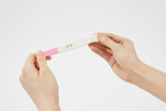 Closeup Of A Person Holding A Positive Pregnancy Test On A White Background