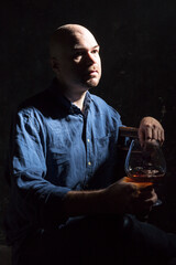 Solid bald man in shirt with glass of whisky