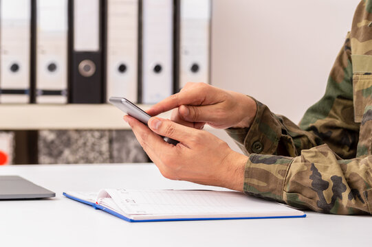Closeup shot of an unrecognizable military man hands with agenda using phone at office