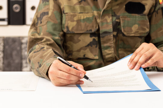 Close up of executive military man hands signing contract on a desk at work