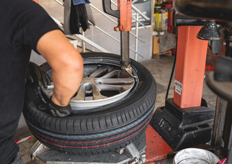Mechanic with pneumatic wrench unscrews the wheel. Male professional mechanic at a car garage...