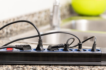 Close up of a plug in an electrical socket on a worktop at kitchen with many connections and...