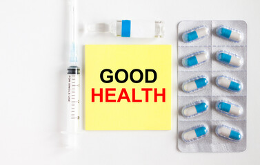 Yellow sticker with text Good Health on a white background with syringes, pills and ampoule