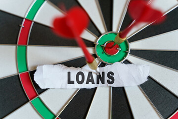 A piece of paper with the text is nailed to the target with a dart - LOANS