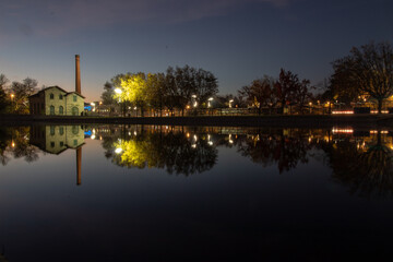 Naklejka premium Museum of electricity in the city of viseu at night, reflecting its image in a local lake, City of Viseu, Portugal