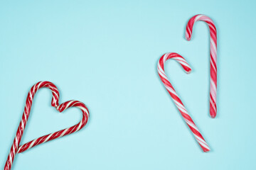 Red and white candy canes in the shape of heart on a light blue background