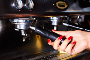 Close-up female barista hand inserts the metal filter in the coffee machine for making hot black coffee