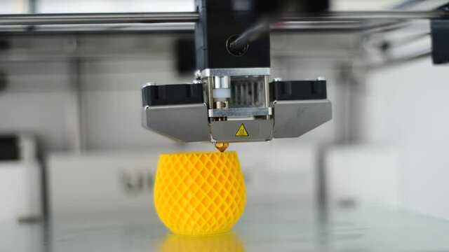 Time lapse of a 3D printer printing a yellow plastic drinking cup