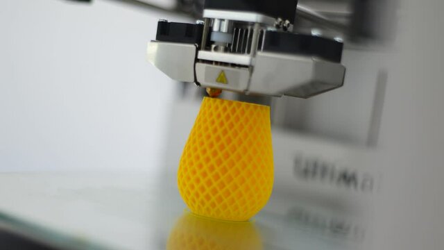 Time lapse of a 3D printer printing a yellow plastic drinking cup