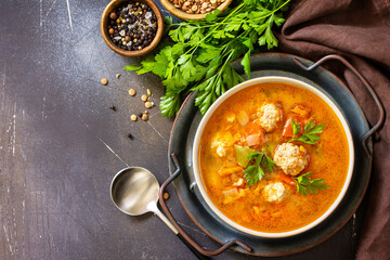 Tomato-lentil soup with meatballs and vegetables on a dark slate table top. Top view flat lay background. Copy space.