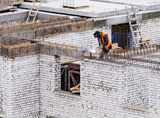 Fototapeta premium Welder worker welding building metal iron reinforcement elements at the construction site