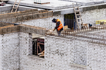 Welder worker welding building metal iron reinforcement elements at the construction site