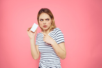 Fototapeta premium Woman with a business card in her hands a striped T-shirt pink background Copy Space advertising