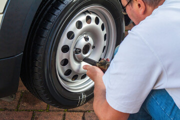 Man changing his own car tire for winter season at home.