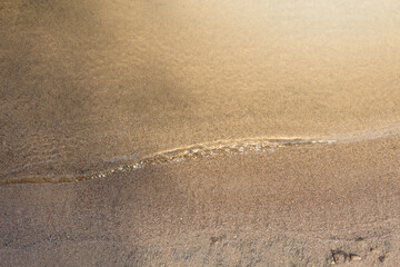 Sandbank close-up with a small wave of clear water
