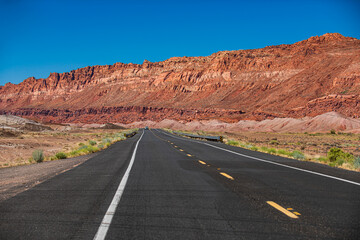 Landscape with rocks, sunny sky with clouds and beautiful asphalt road in the evening in summer. American roadtrip.
