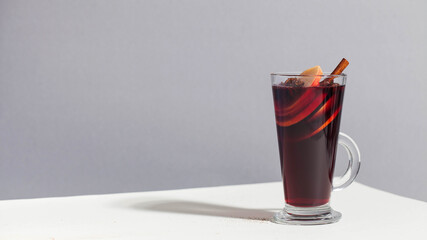 Mulled wine in a glass with a stick of cinnamon, spices. photo with hard light.
