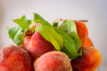 Few ripe peaches with green leaves on a white background with a copy space