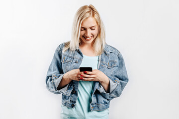 Beautiful young cute girl smiling and looking at phone on gray isolated background