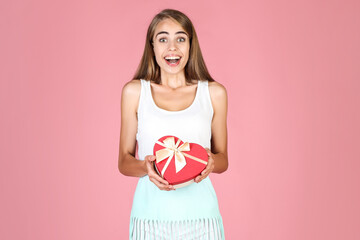 Fototapeta na wymiar Young girl holding gift box on pink background