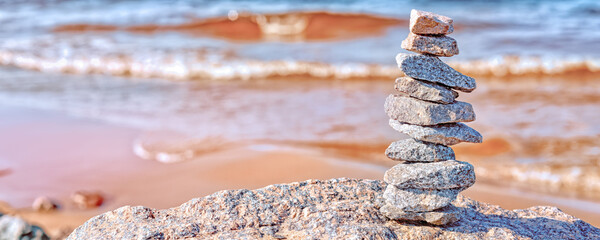 Zen like pyramid of stones against defocused warm sea