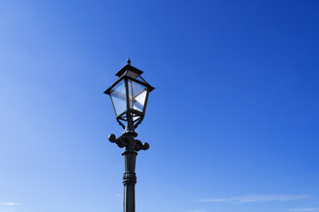 Retro street lamp on clear blue sky background.