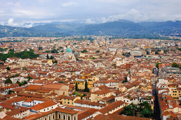 Fototapeta na wymiar View of Florence and the mountains from the dome of the cathedral. Many houses with red roofs and a beautiful cathedral. There is fog over the mountains.