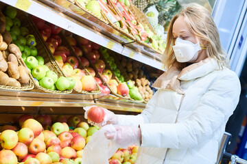 woman in mask and protective gloves buying food in shop at coronavirus epidemic