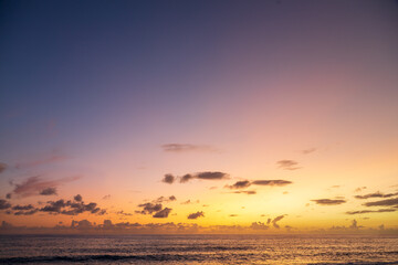 Obraz premium Dramatic sea shore sunset with sun setting down at the cloudy skyline with orange and vivid blues.
