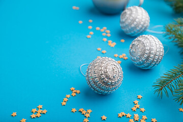 Christmas or New Year composition. Decorations, silver balls, fir and spruce branches, on a blue background. Side view, copy space.