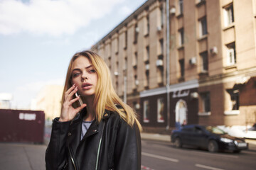 Cropped view of blonde woman with mobile phone on the street near the building 