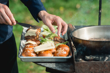 Chef making beef burgers outdoor on food festival event. Street food ready to serve on a food stall.