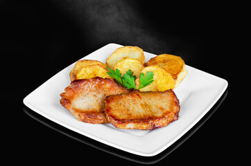 Hot roast meat with potatoes on a black background, steam rises. Selective focus