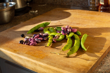 Heirloom scarlet runner beans and pods on light wooden cutting board