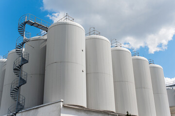 Rows of brewing tanks against the sky. Industrial beer production