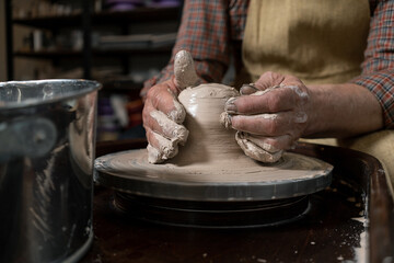pottery, workshop, ceramics art concept - closeup on male hands sculpt new utensil with a tools and water, man's fingers work with potter wheel and raw fireclay, front close view