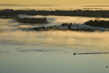 BOAT FLOATS ON THE RIVER THROUGH FOG